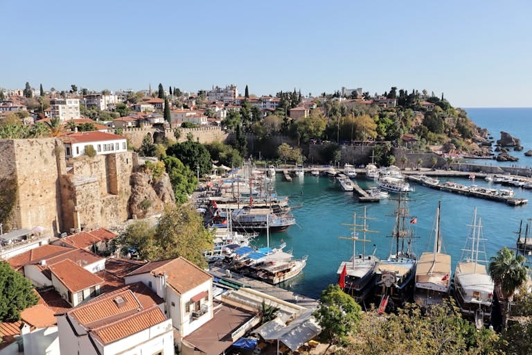 A stunning aerial view of Antalya's historic harbor with yachts and surrounding architecture on a sunny day.