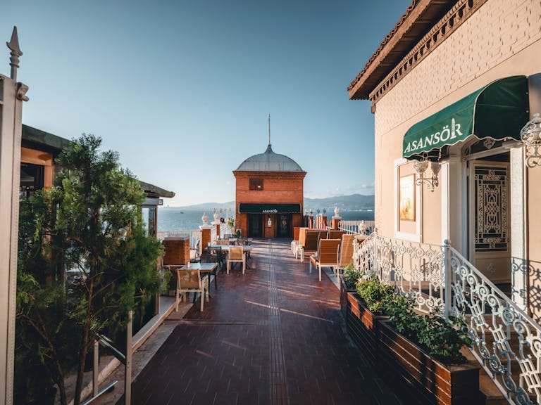 Explore the charming walkway and iconic Asansör Tower in İzmir, Türkiye, under clear skies.