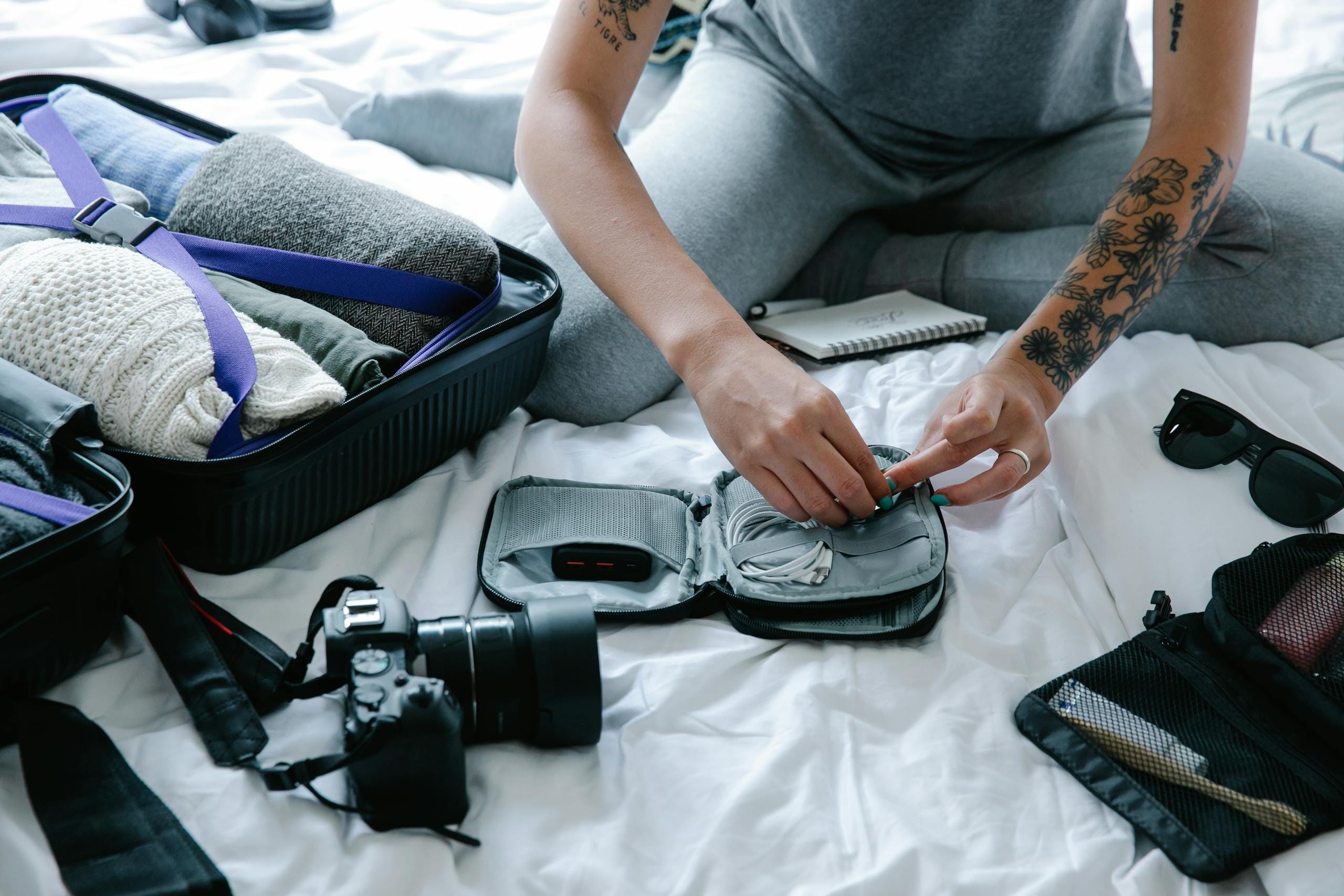 महिला सूटकेस और तकनीक के सामान पैक कर रही है, यात्रा की तैयारी कर रही है। Turkey Travel Checklist: जाने से पहले करने योग्य सभी बातें