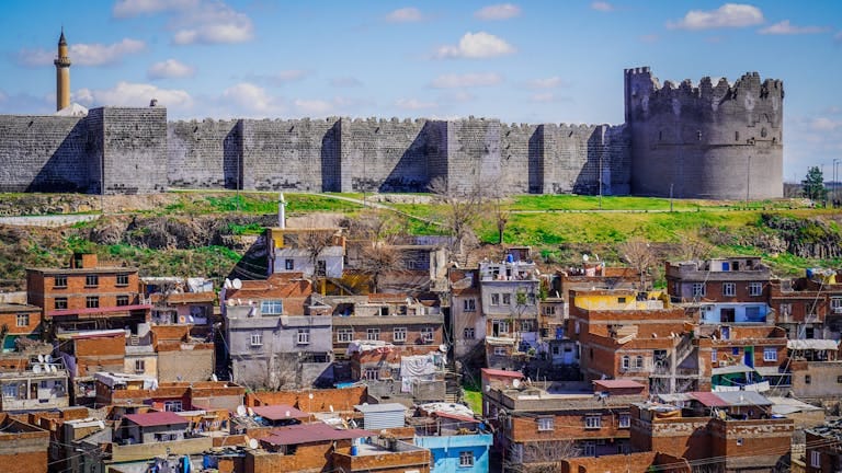 The ancient city walls of Diyarbakir tower over a bustling urban landscape.