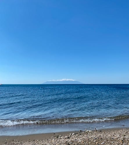 Kalme Egeïsche Zee met uitzicht op een ver eiland onder een helderblauwe hemel. De Egeïsche kust van Turkije.